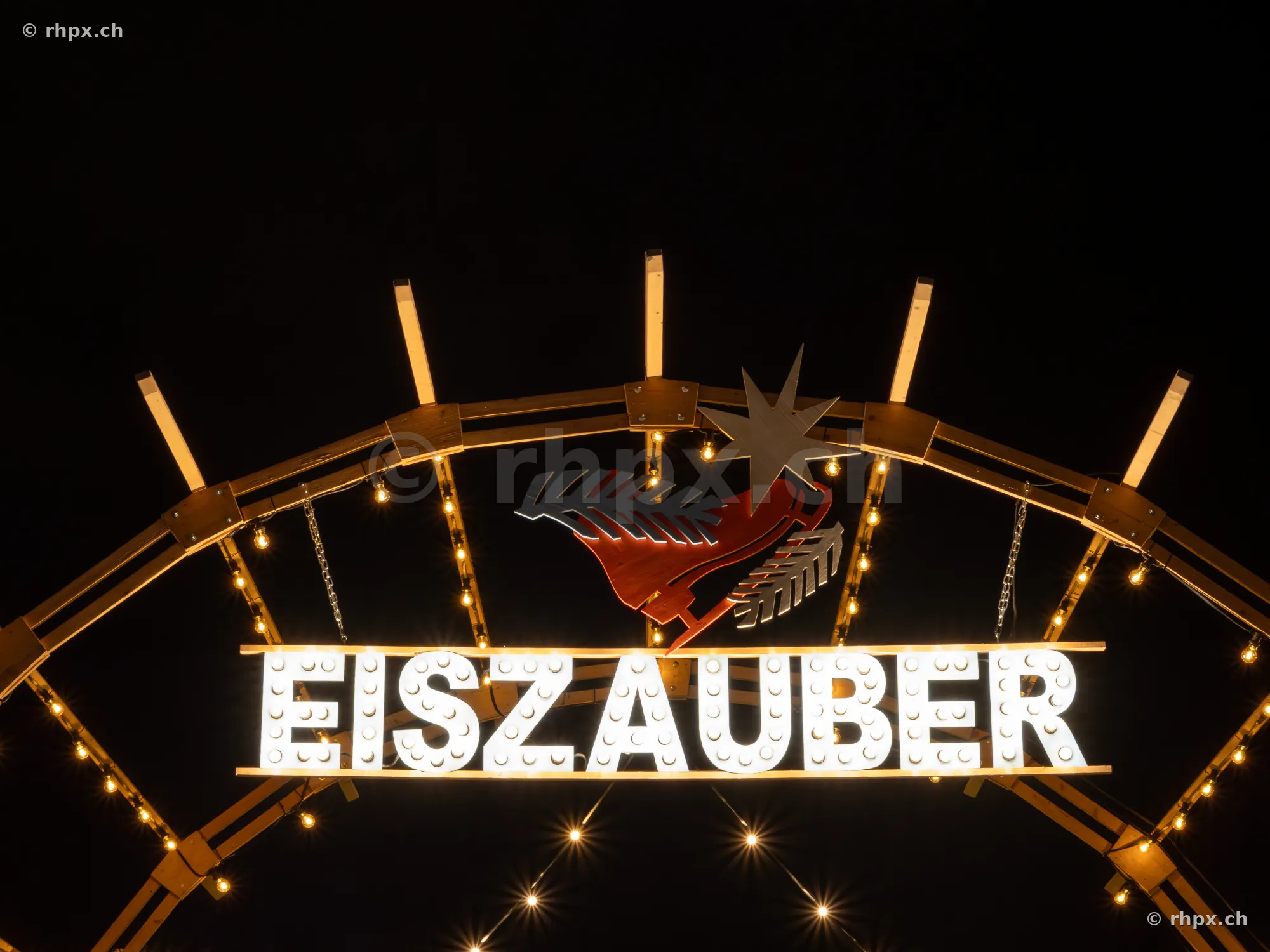 Illuminated Eiszauber sign with star motif at night in Lucerne
