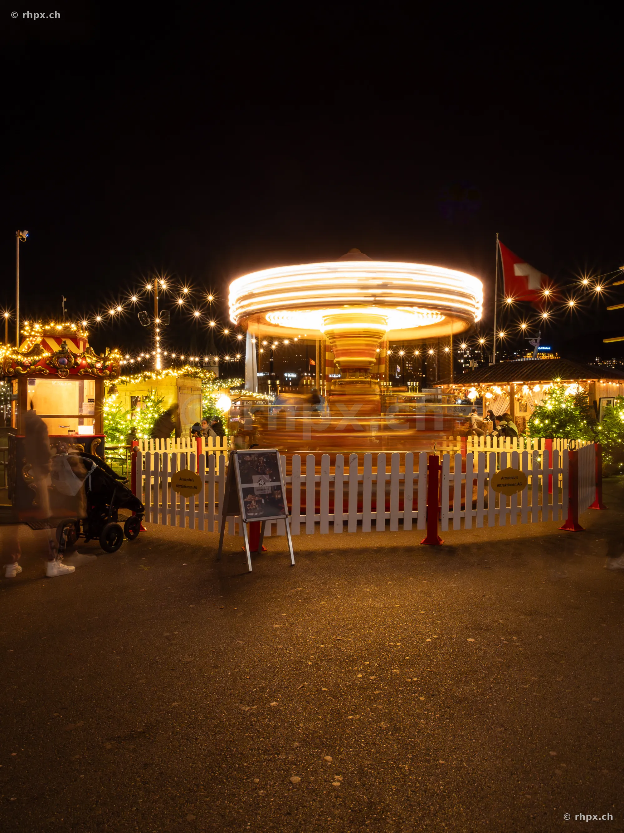 Christmas market with illuminated rotating merry-go-round at night in Lucerne