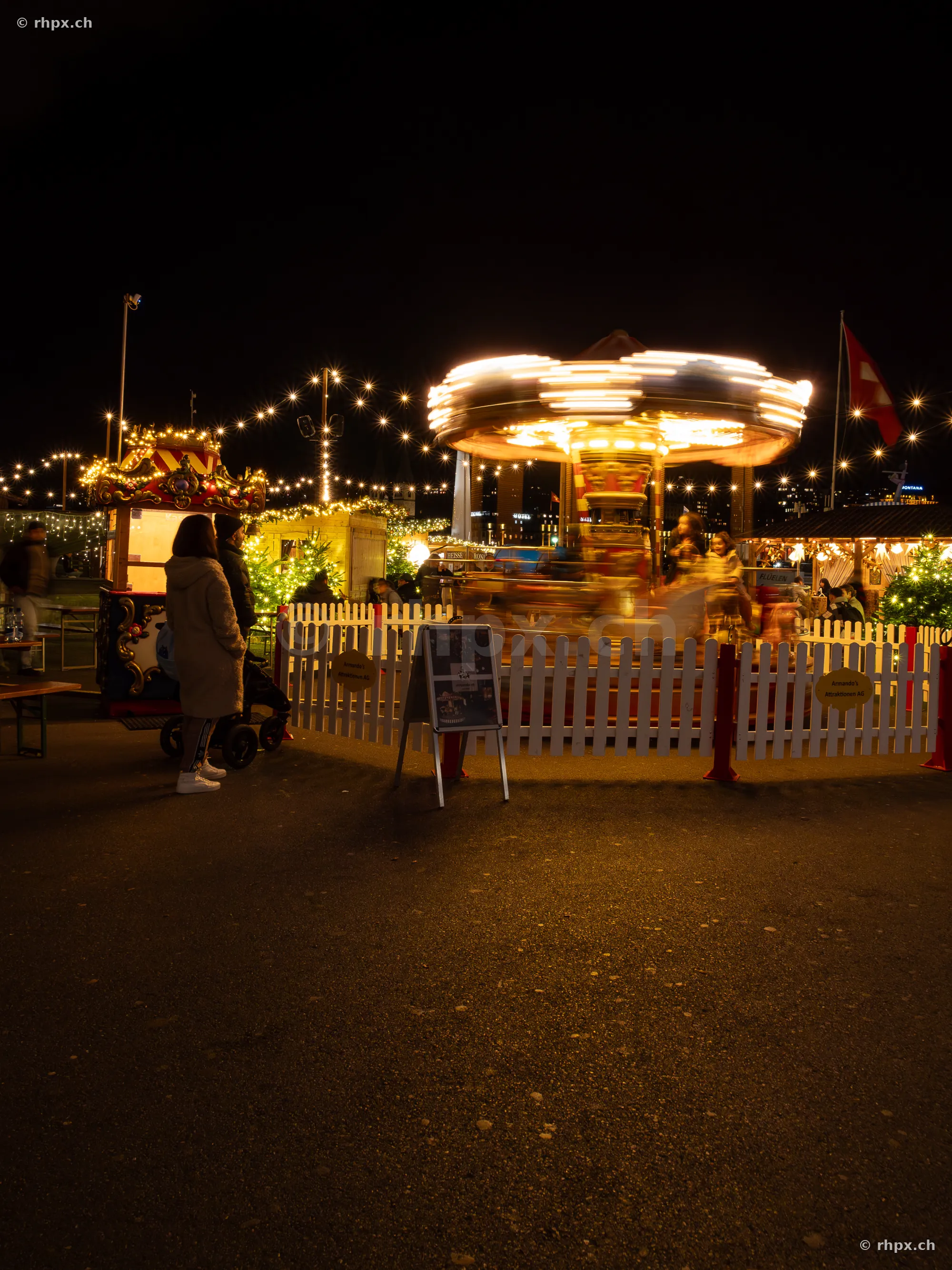 Ein beleuchtetes, sich drehendes Karussell auf einem Weihnachtsmarkt in Luzern bei Nacht.