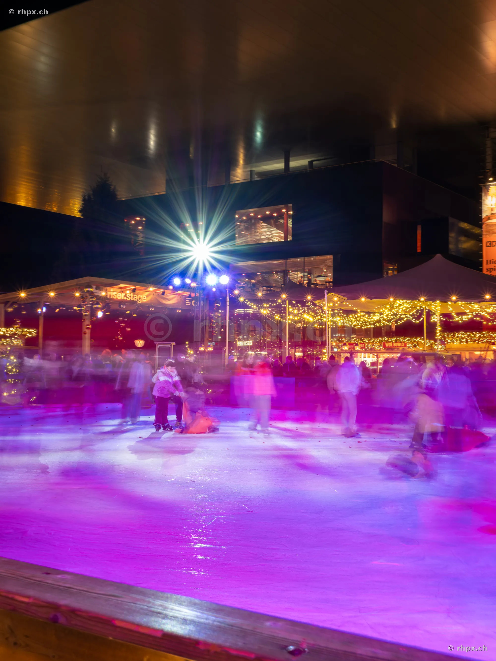 Ice rink with people in front of KKL Lucerne at night