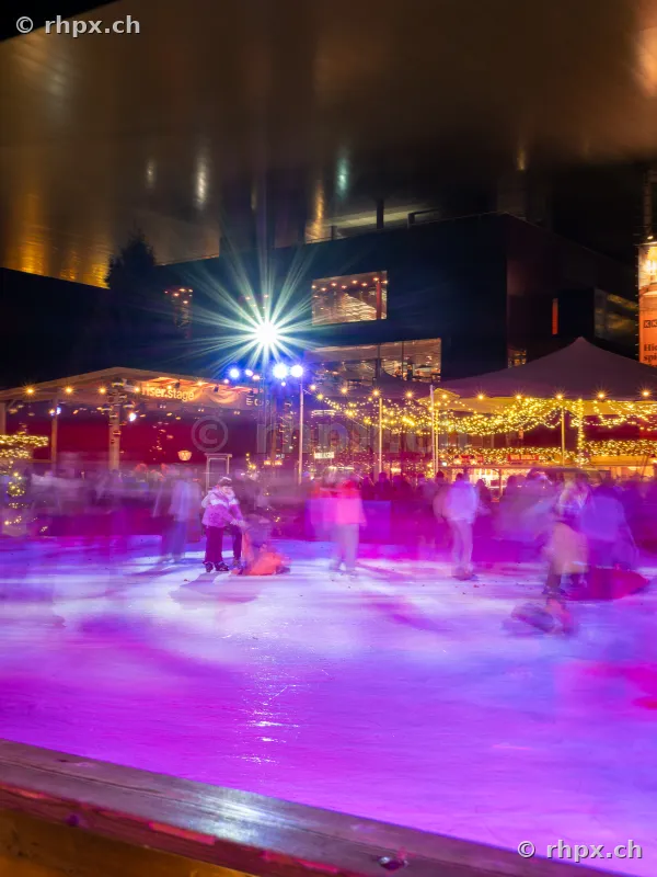 Ice rink with people in front of KKL Lucerne at night