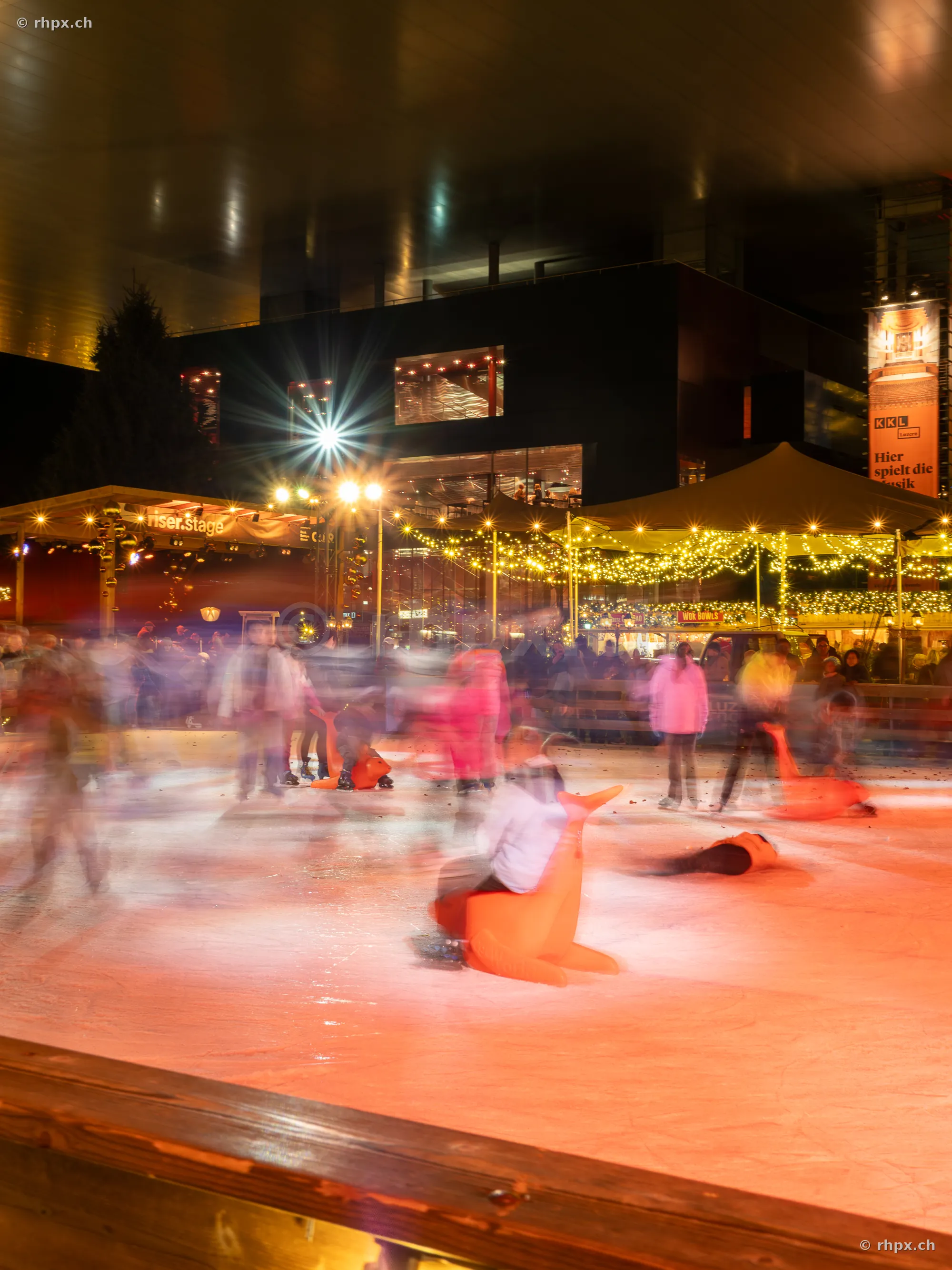 Visitors on the ice rink in front of the illuminated KKL Lucerne during the Christmas season
