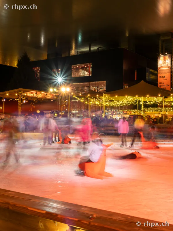 Visitors on the ice rink in front of the illuminated KKL Lucerne during the Christmas season