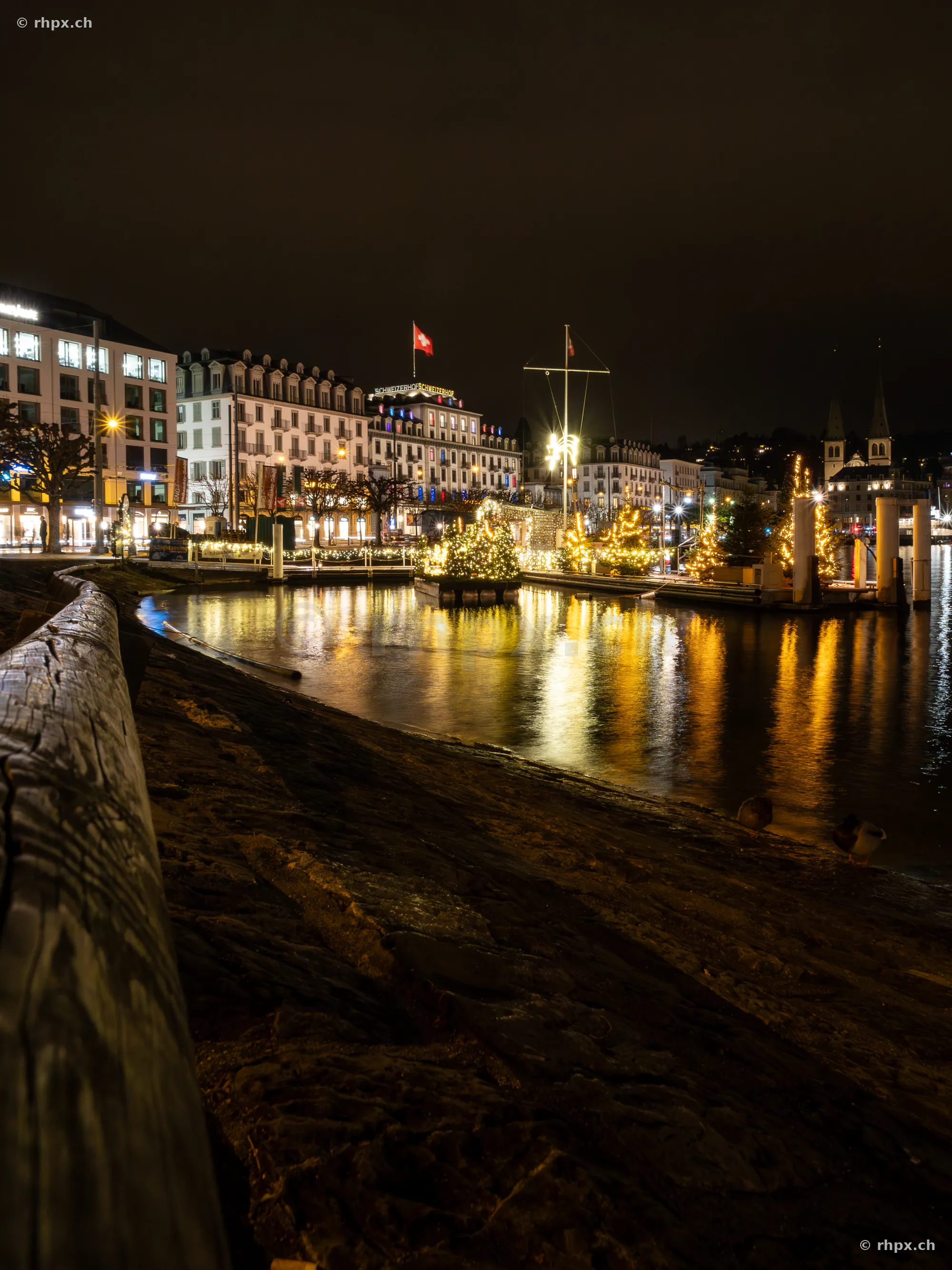 Weihnachtlich beleuchtetes Seeufer in Luzern bei Nacht mit Reflexionen im Wasser