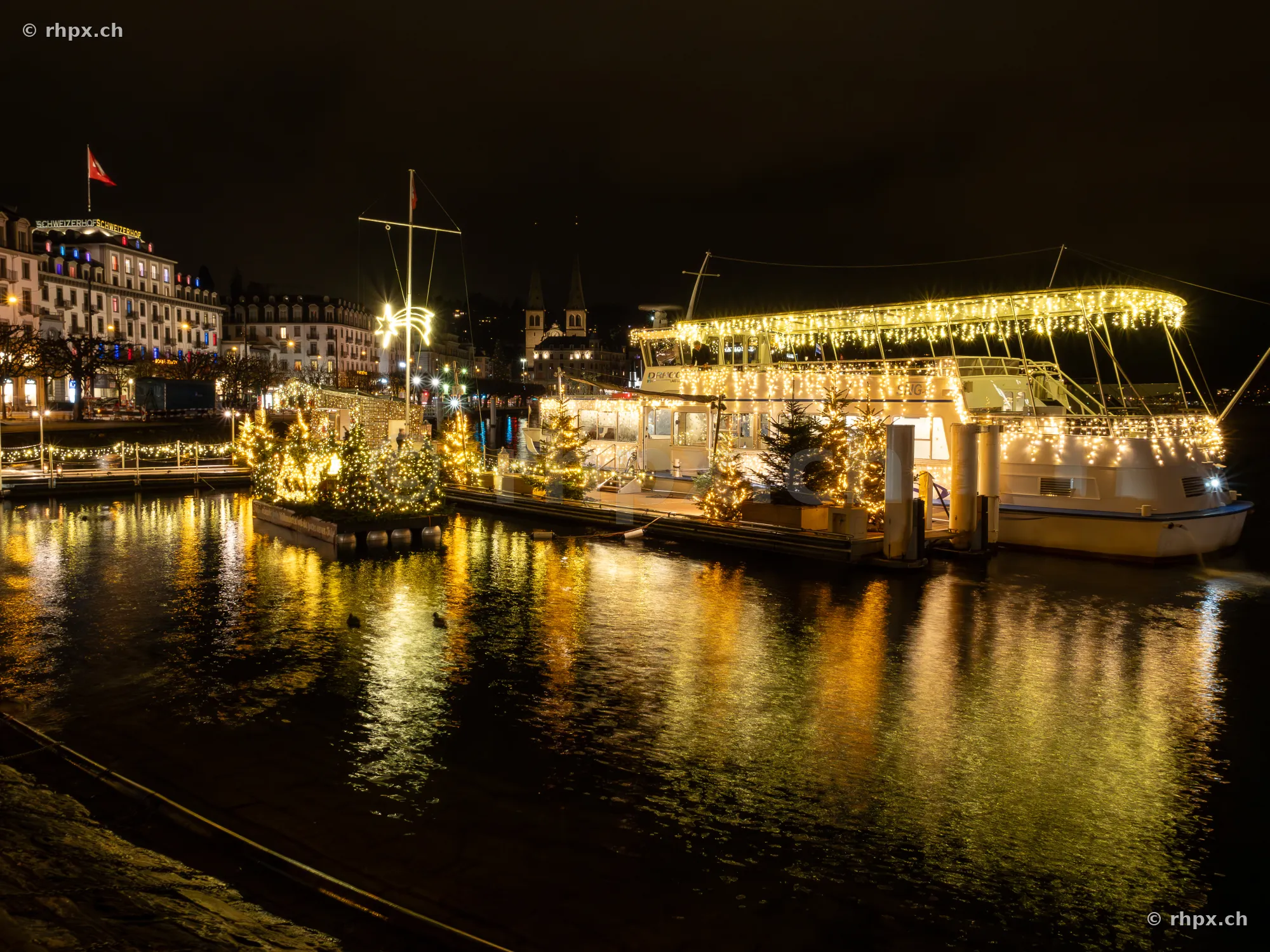 Festively illuminated passenger boat at the Lucerne quay at night with reflections in Lake Lucerne