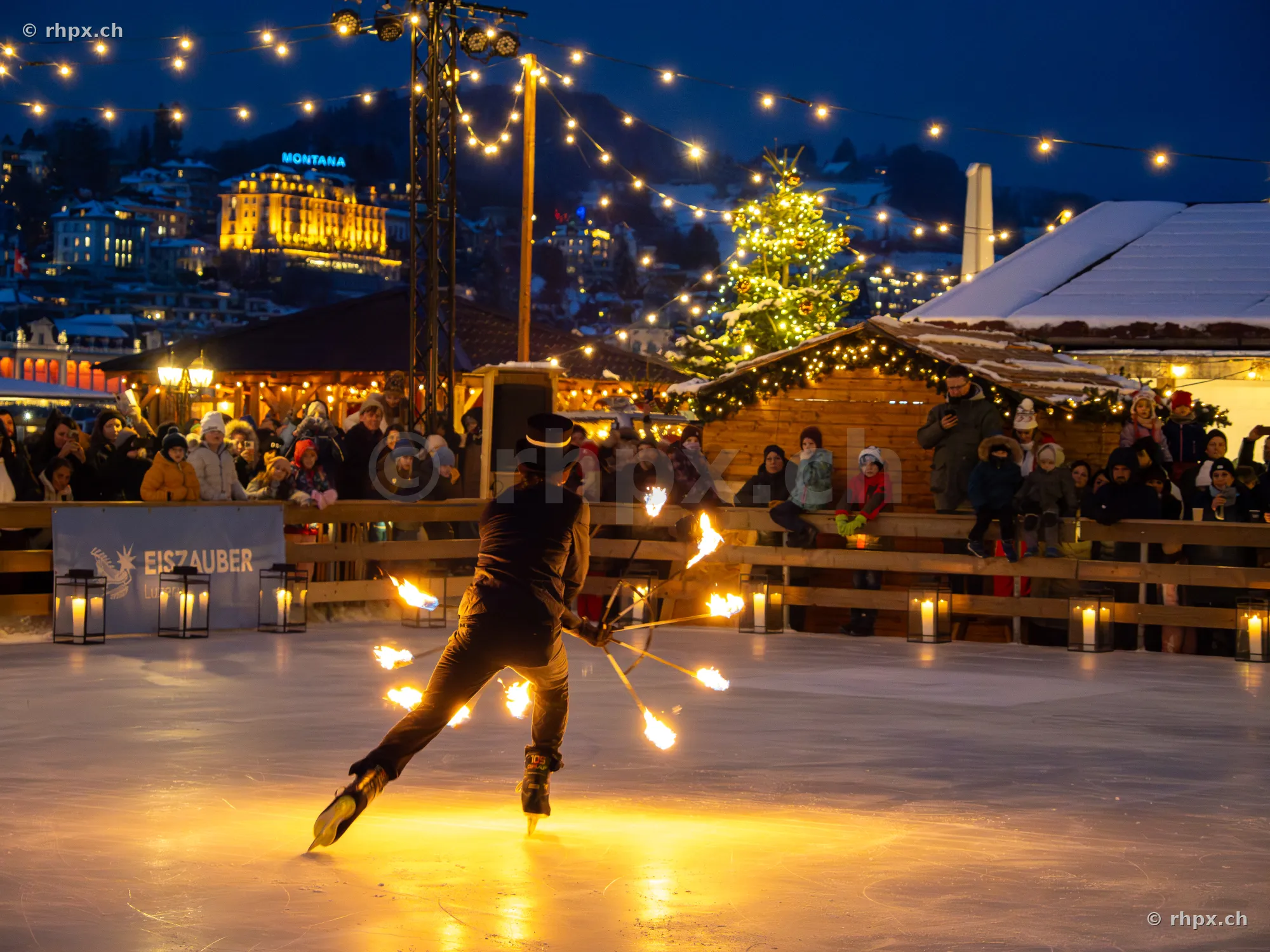 A performer presents a fire show on the ice rink at Eiszauber Lucerne