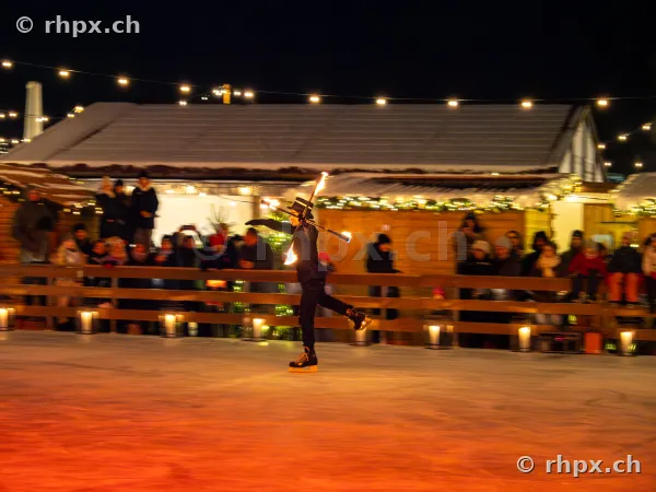 Person wearing a top hat performing a fire show on the ice rink at the Christmas market in Lucerne