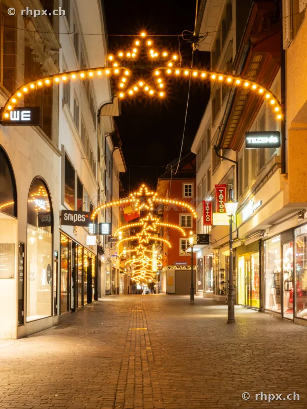 Weihnachtsbeleuchtung mit Sternen in einer menschenleeren Einkaufsstrasse in der Luzerner Altstadt bei Nacht