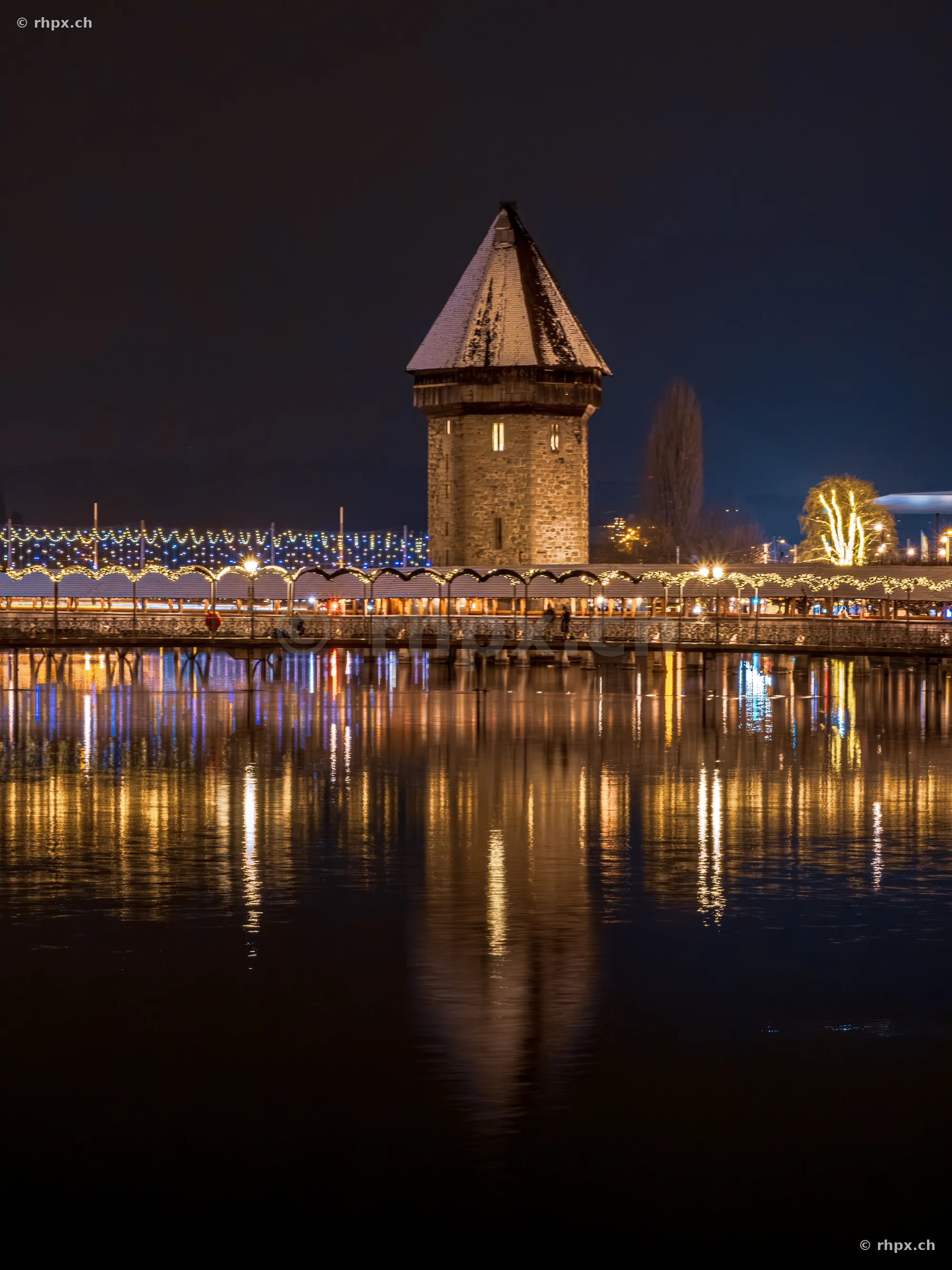 Wasserturm of the Chapel Bridge in Lucerne with festive Christmas lighting at night.