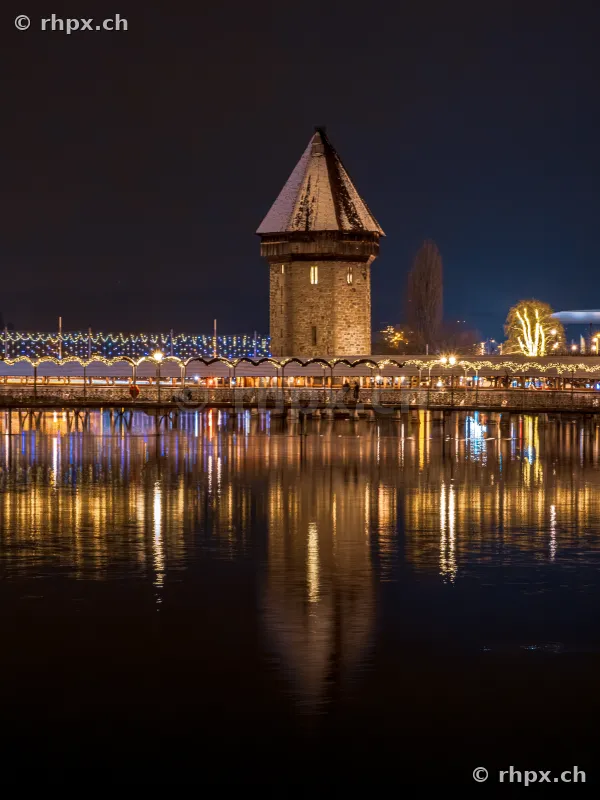 Wasserturm of the Chapel Bridge in Lucerne with festive Christmas lighting at night.