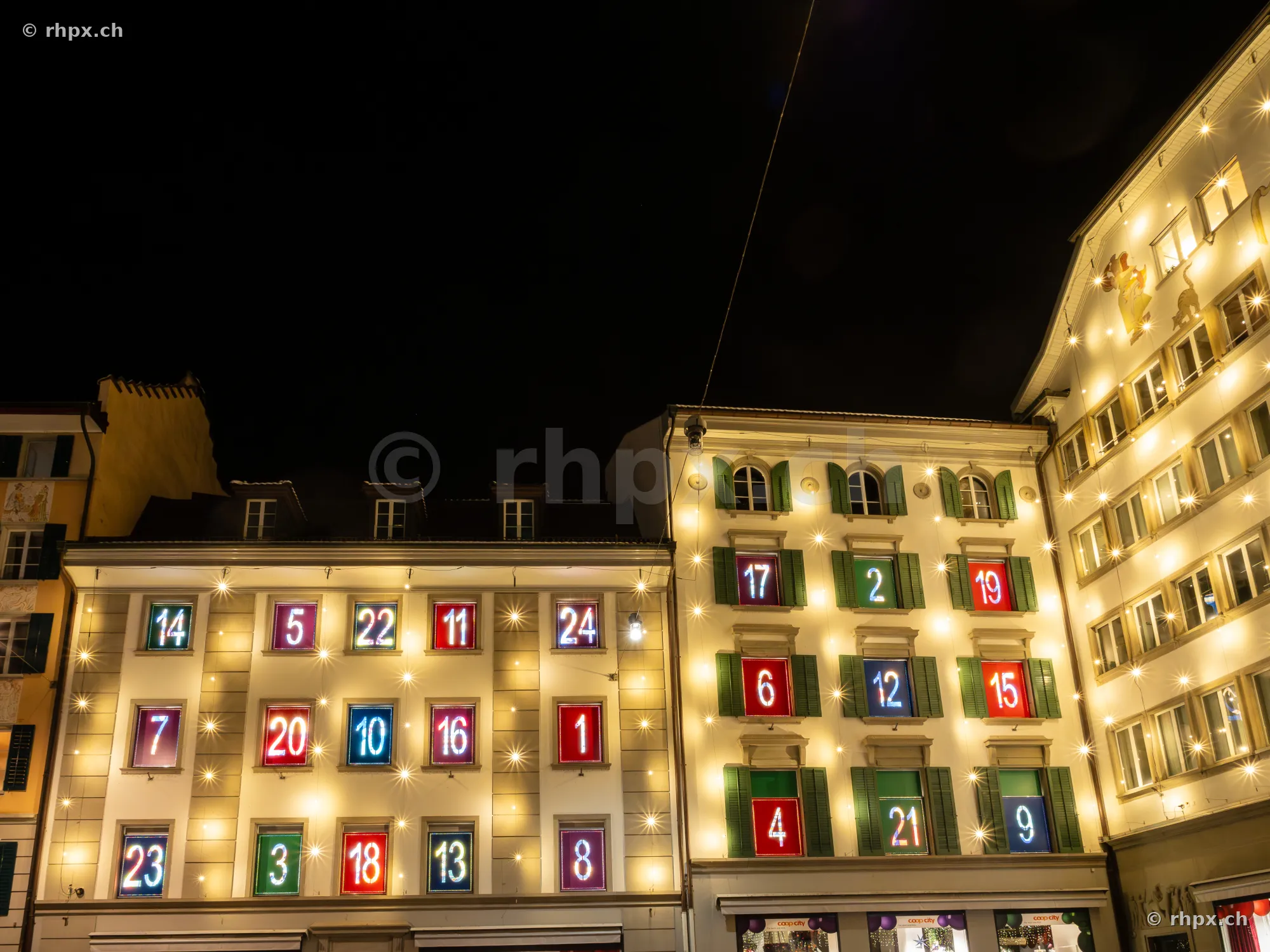 Beleuchtete Fenster als Adventskalender an Häuserfassaden in der Altstadt von Luzern bei Nacht.