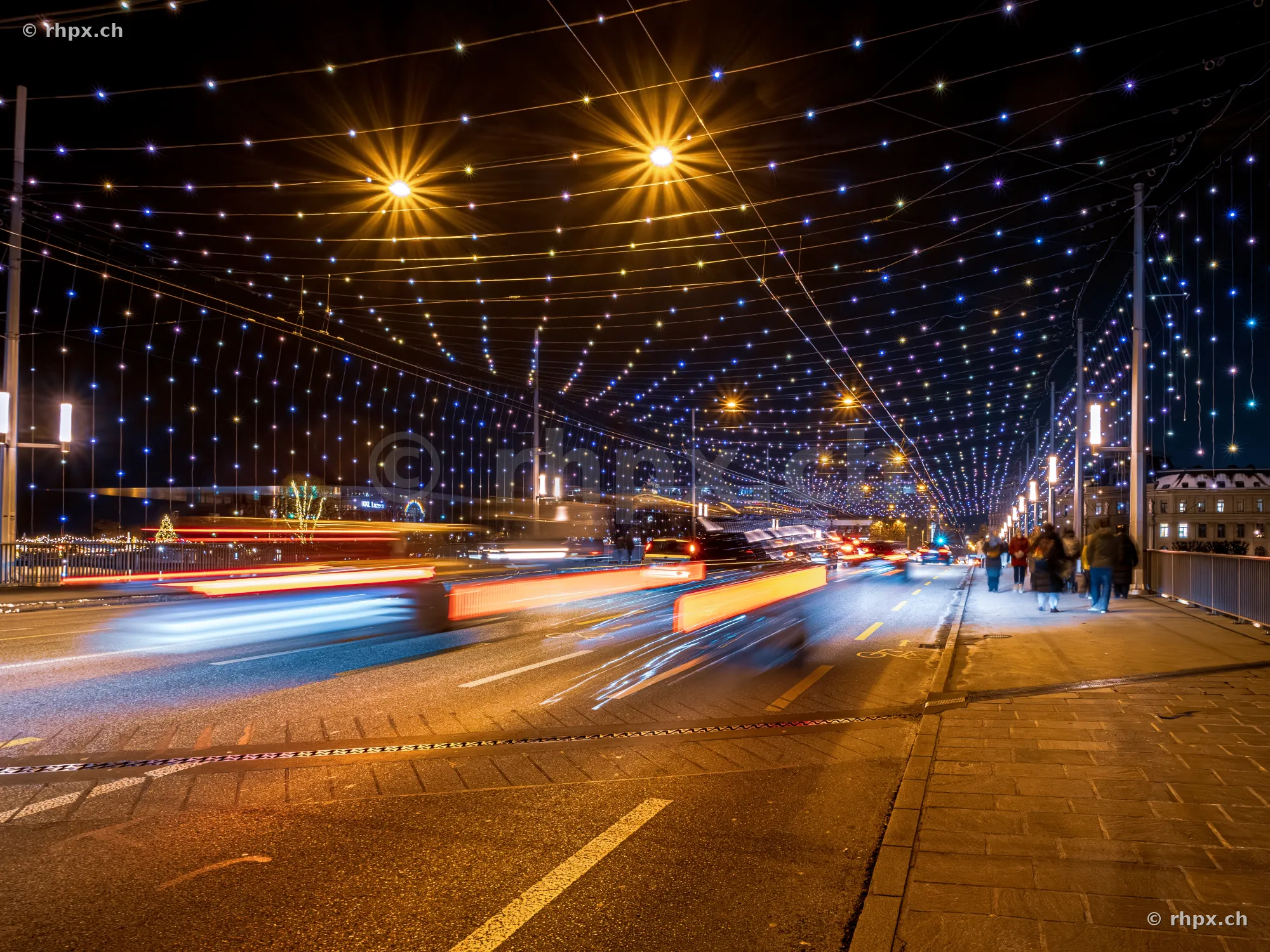 Lichtinstallation über der nächtlichen Seebrücke in Luzern mit vorbeifahrenden Fahrzeugen