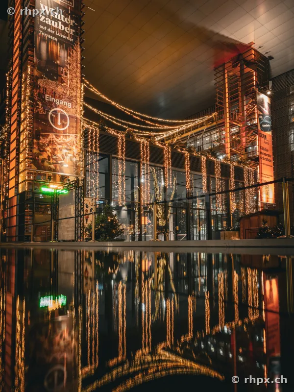 Illuminated facade of the KKL Lucerne during the Christmas season with reflection