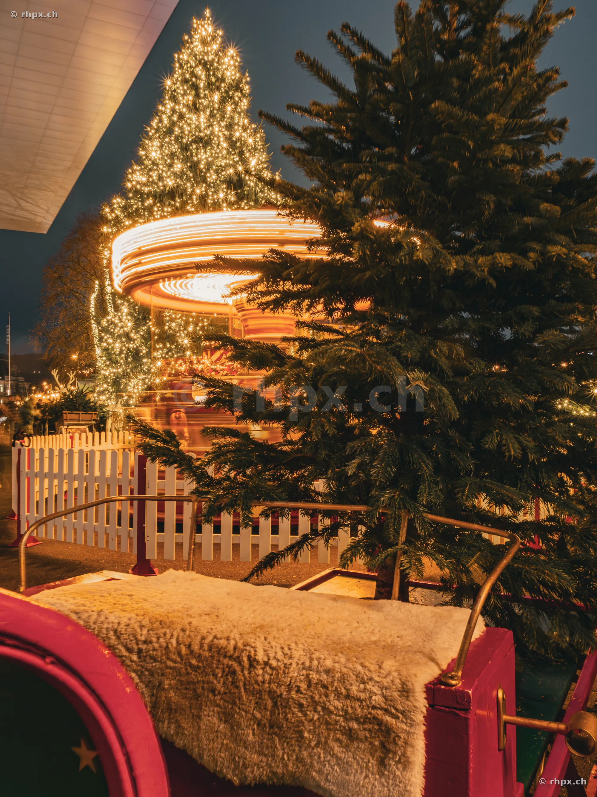 Festively lit carousel and Christmas tree seen from a sleigh at the Lucerne lakefront at night