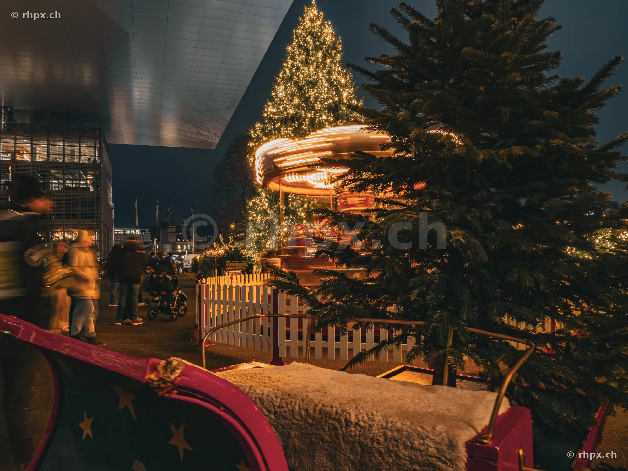 Weihnachtsmarkt vor dem KKL Luzern mit beleuchtetem Karussell und Tannenbaum in der Nacht