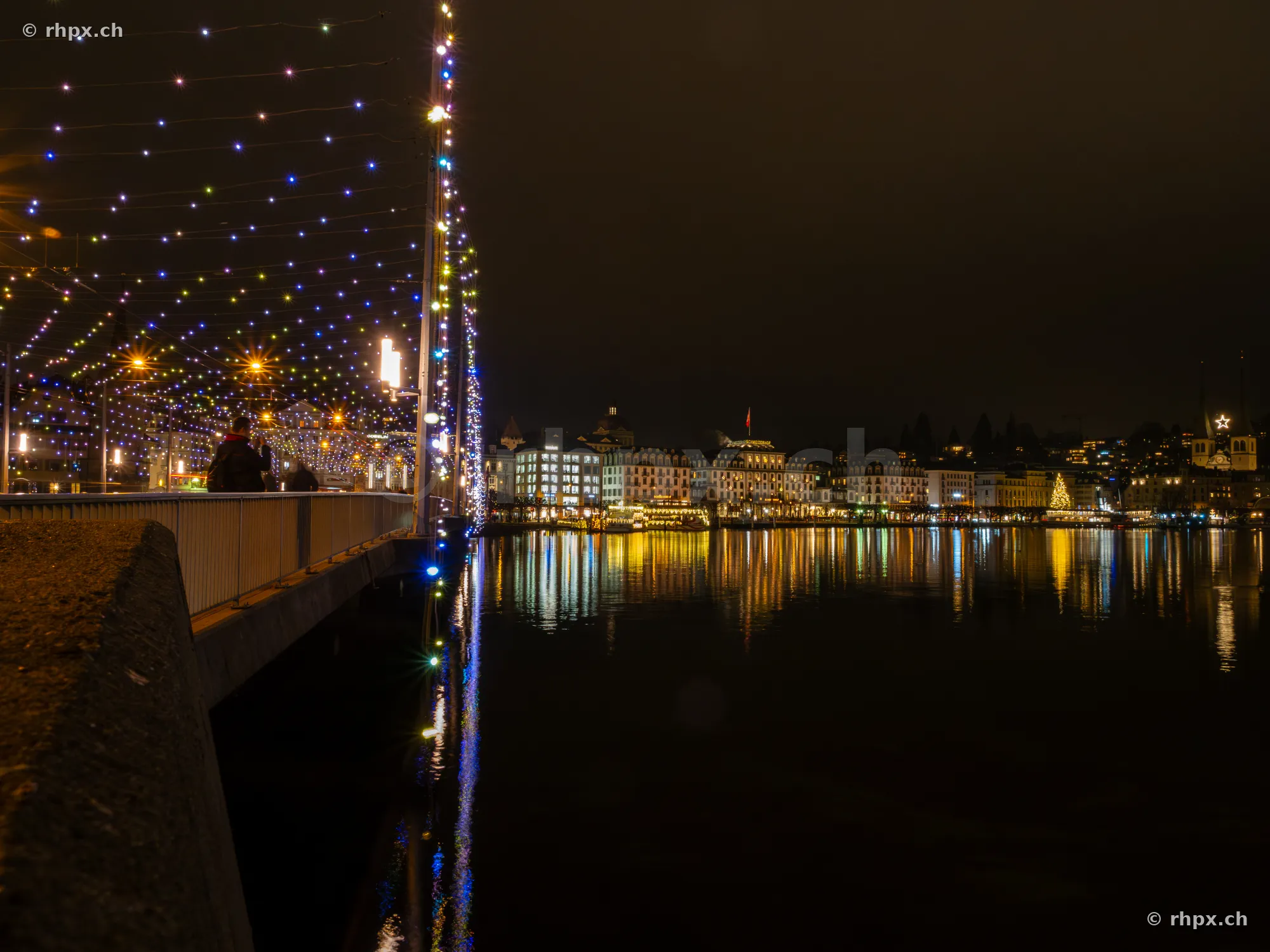 Night view of the Seebrücke in Lucerne with colorful Christmas lighting and the illuminated lakeshore