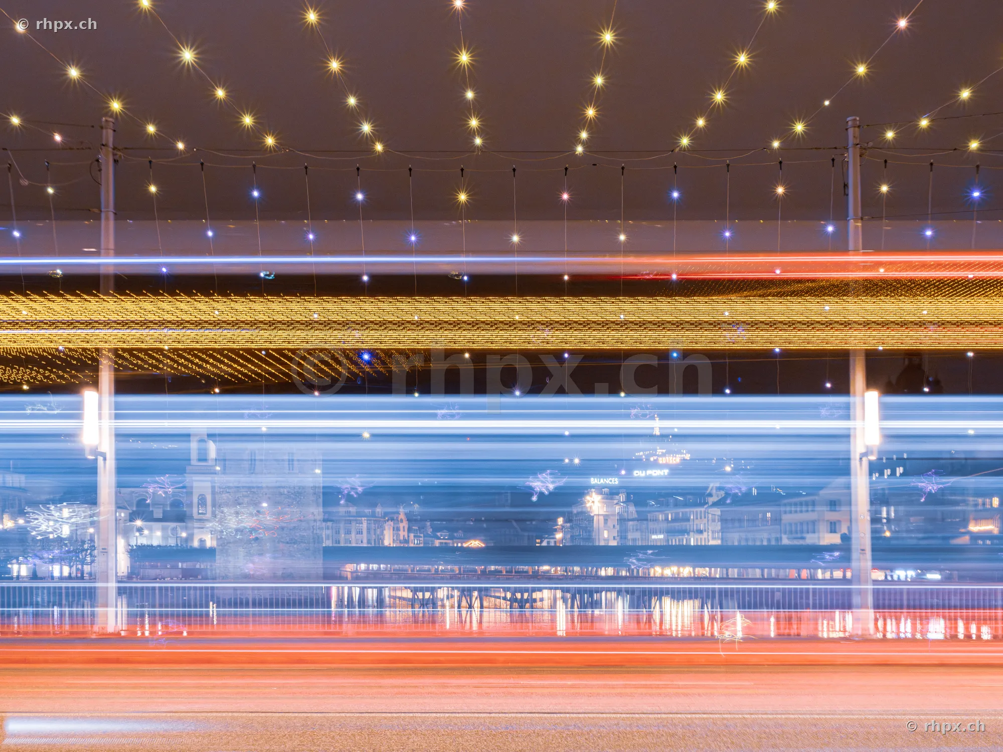 Long exposure of vehicle light trails in front of the festive illuminated scenery of Lucerne city at the lake