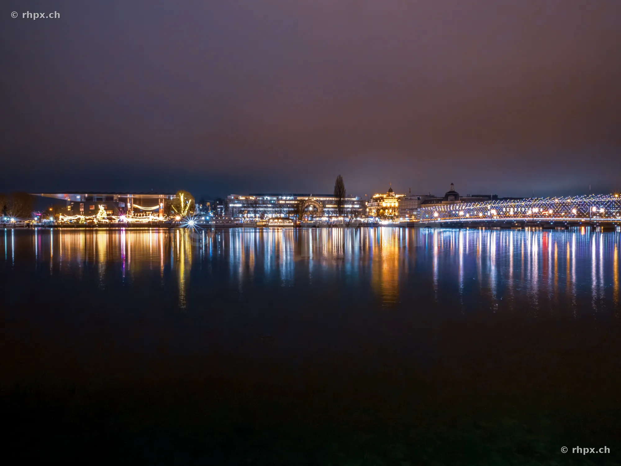 Night view of the illuminated waterfront of Lucerne with reflections in Lake Lucerne.