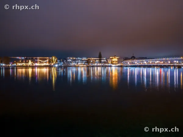 Nächtlicher Blick auf das beleuchtete Ufer von Luzern mit Reflexionen im Vierwaldstättersee.