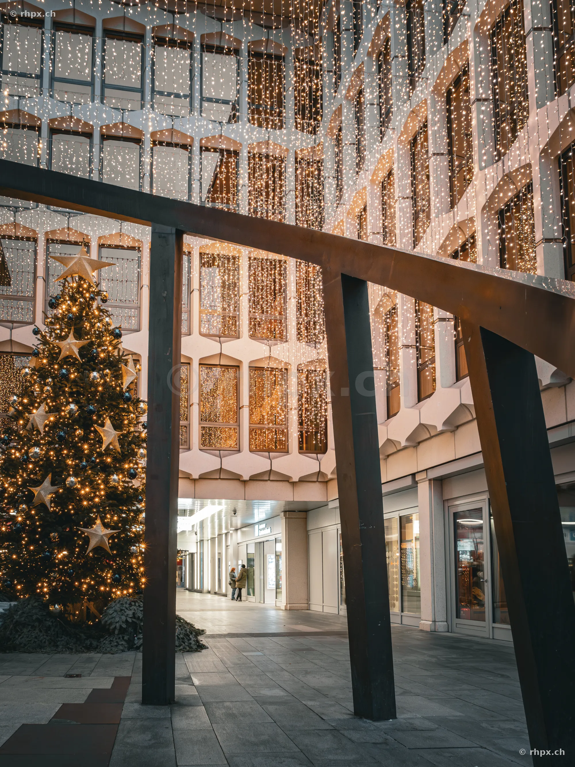 Illuminated Christmas tree and fairy lights on a building facade in a Lucerne courtyard