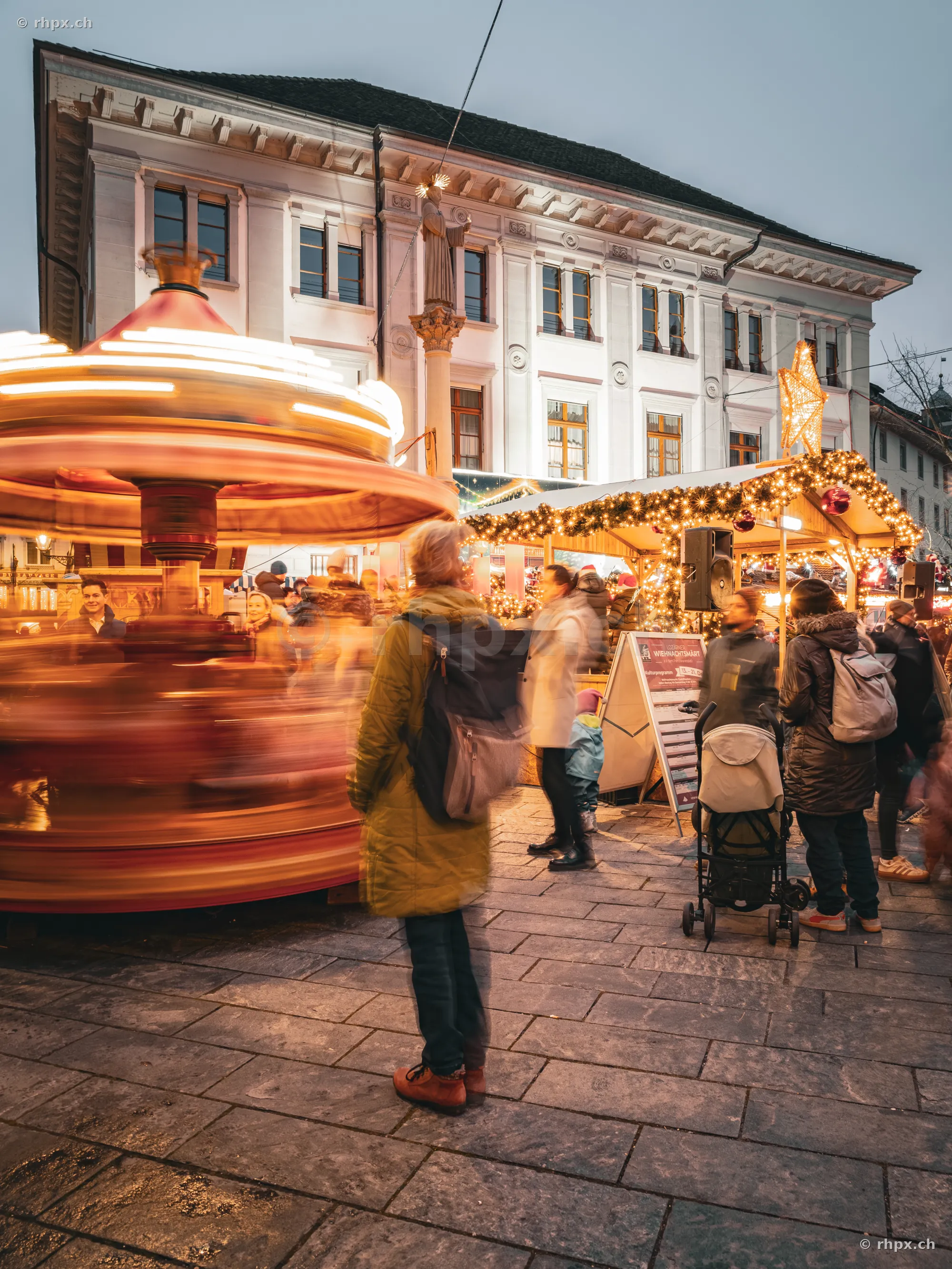 Personen vor einem beleuchteten Kinderkarussell auf dem Luzerner Weihnachtsmarkt