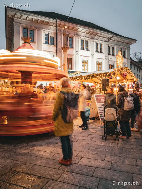 People in front of an illuminated merry-go-round at the Lucerne Christmas market