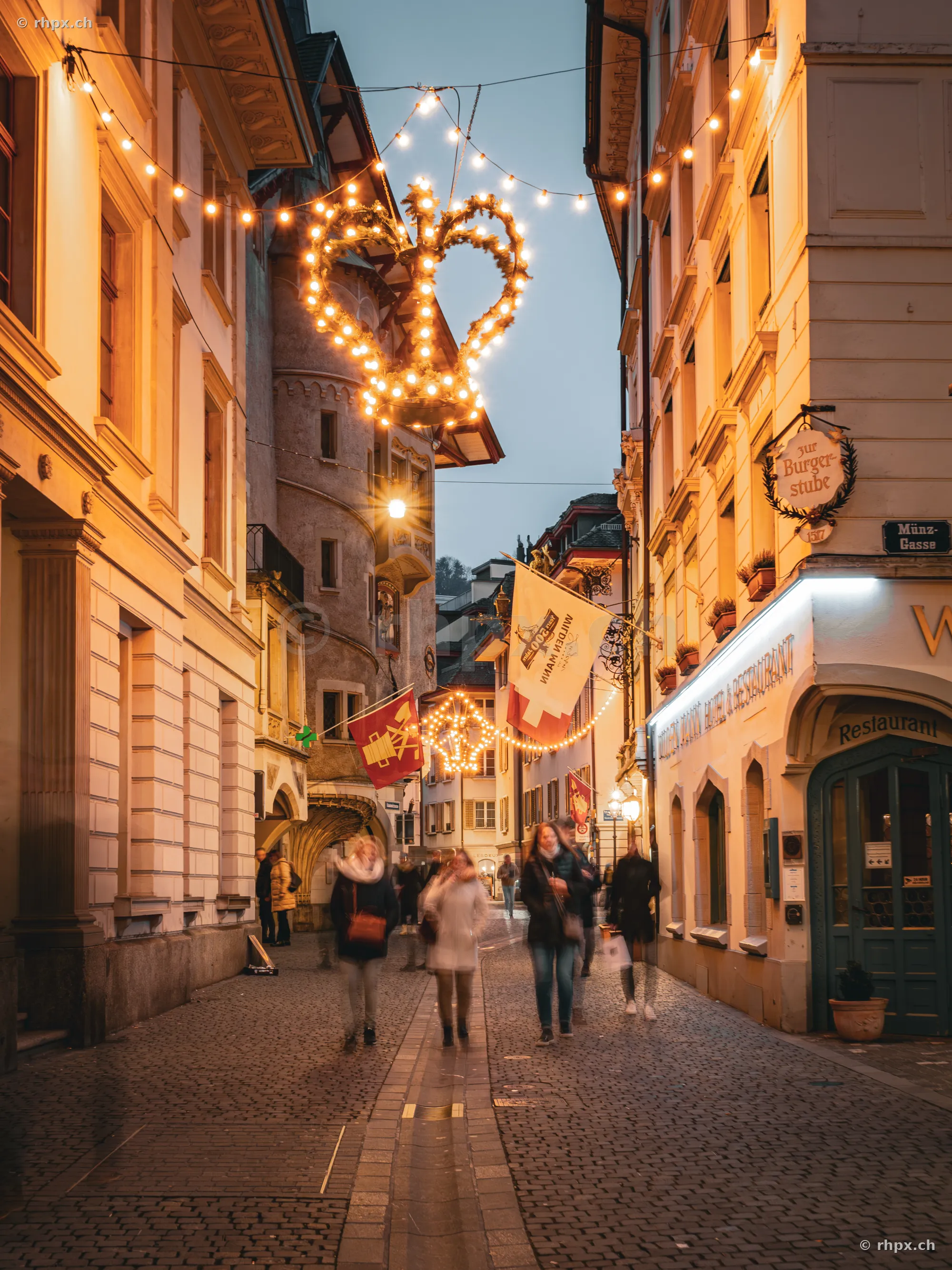 Menschen in der festlich beleuchteten Münzgasse in Luzern zur Weihnachtszeit