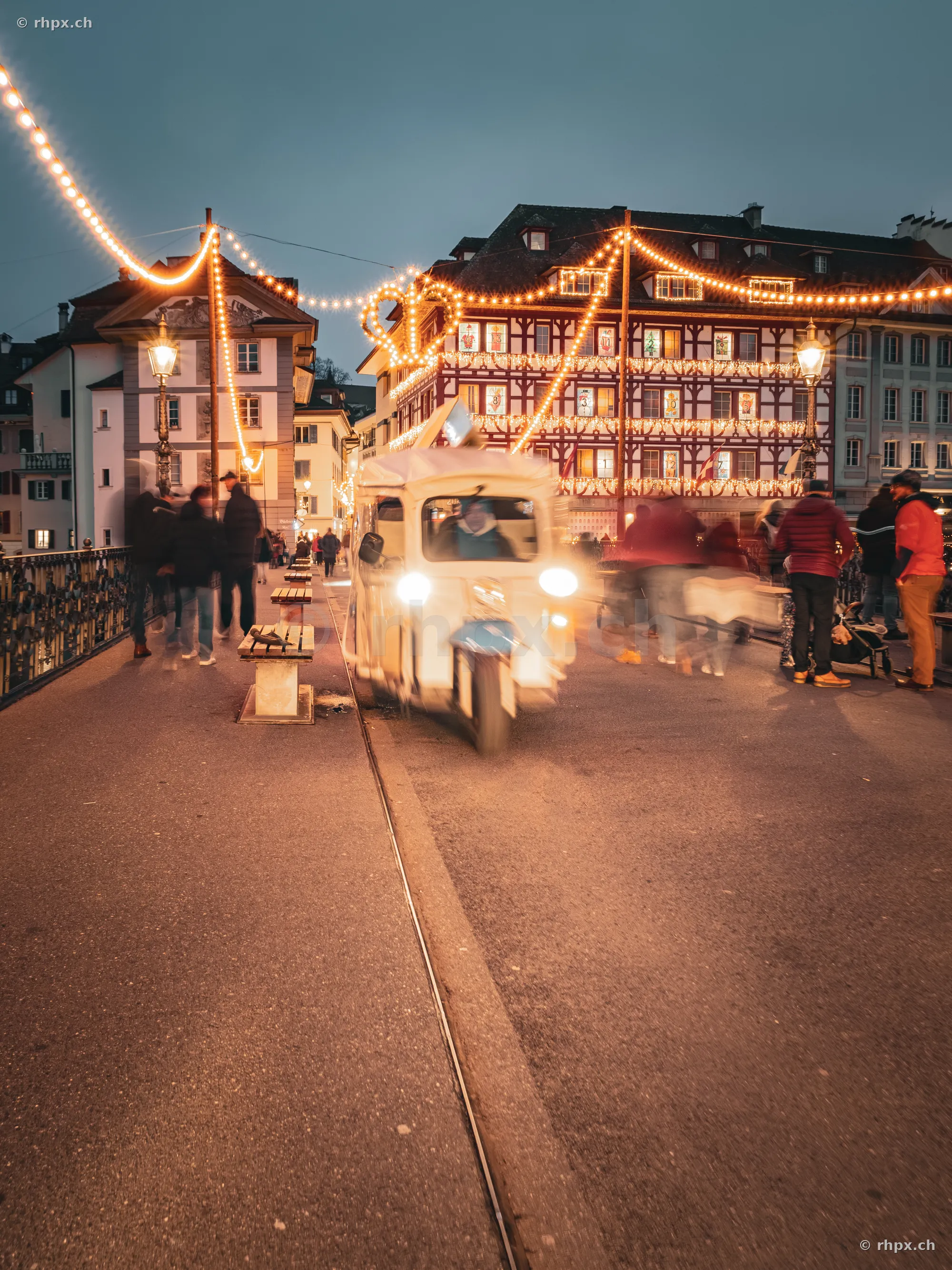Beleuchtete Altstadtgasse in Luzern mit einem fahrenden Lieferfahrzeug in der Dämmerung