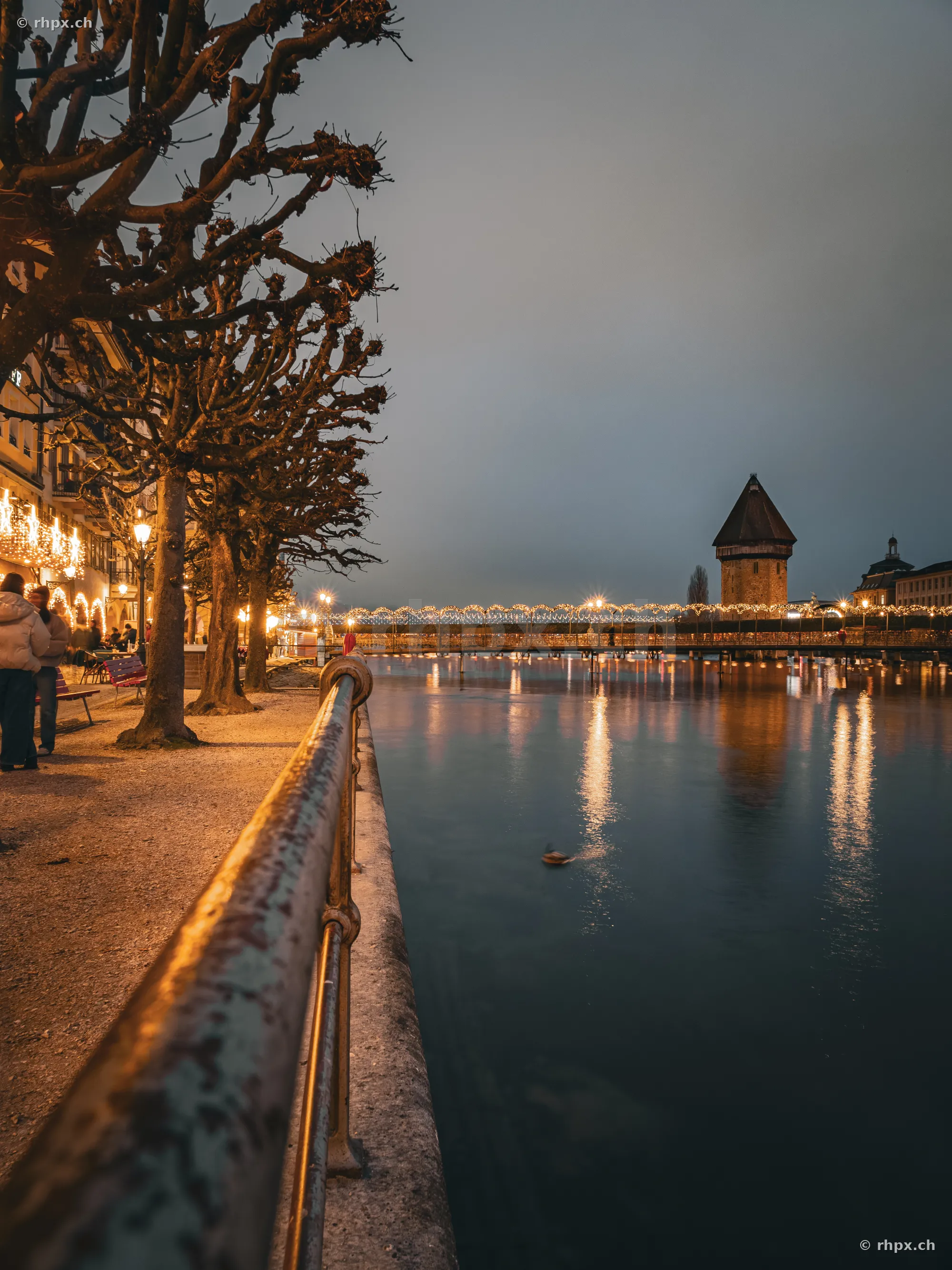 Lucerne riverfront at night with Christmas lighting and Chapel Bridge in the background.