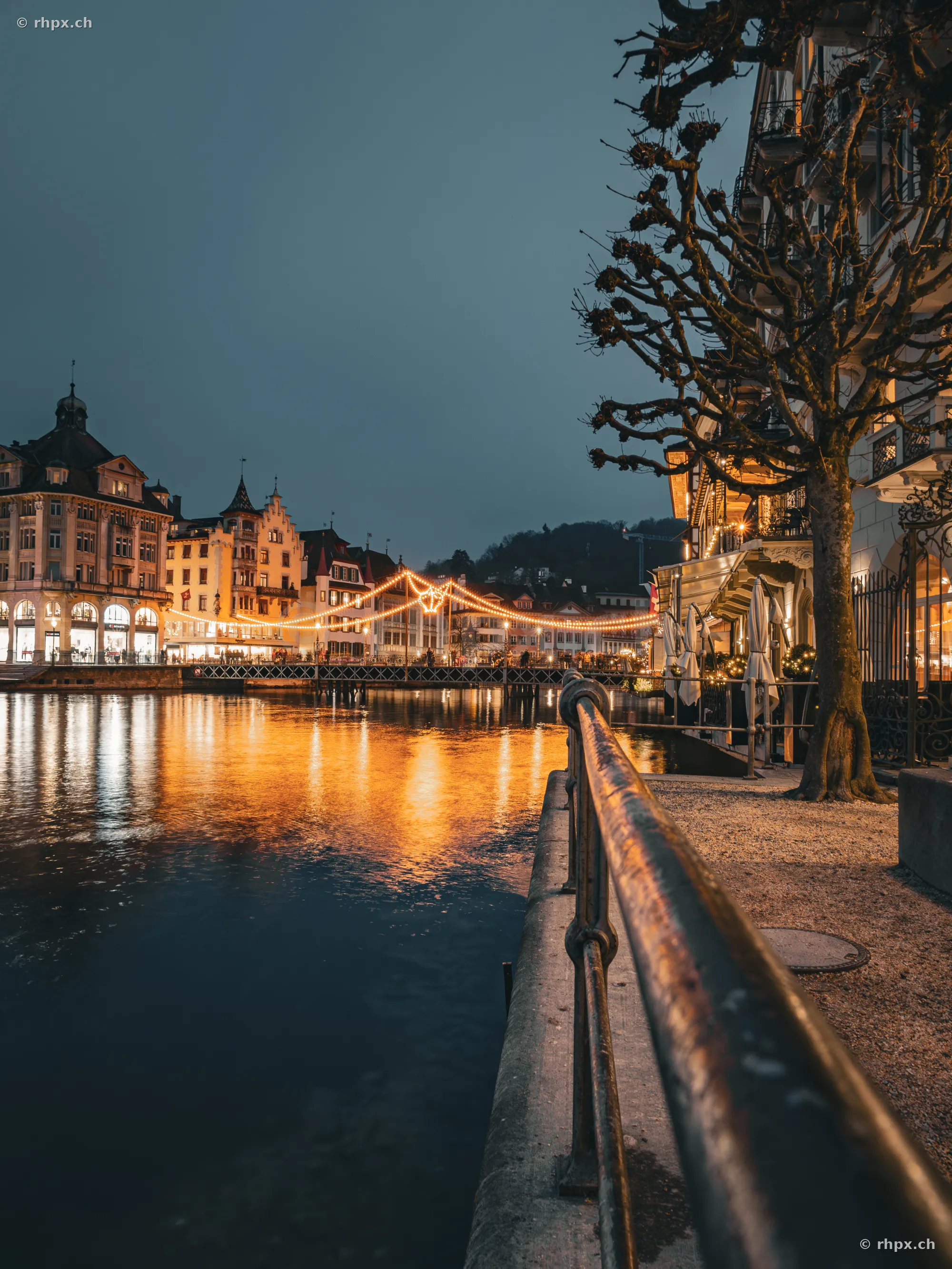 Blick über die Reuss auf die beleuchtete Uferpromenade von Luzern in der Vorweihnachtszeit