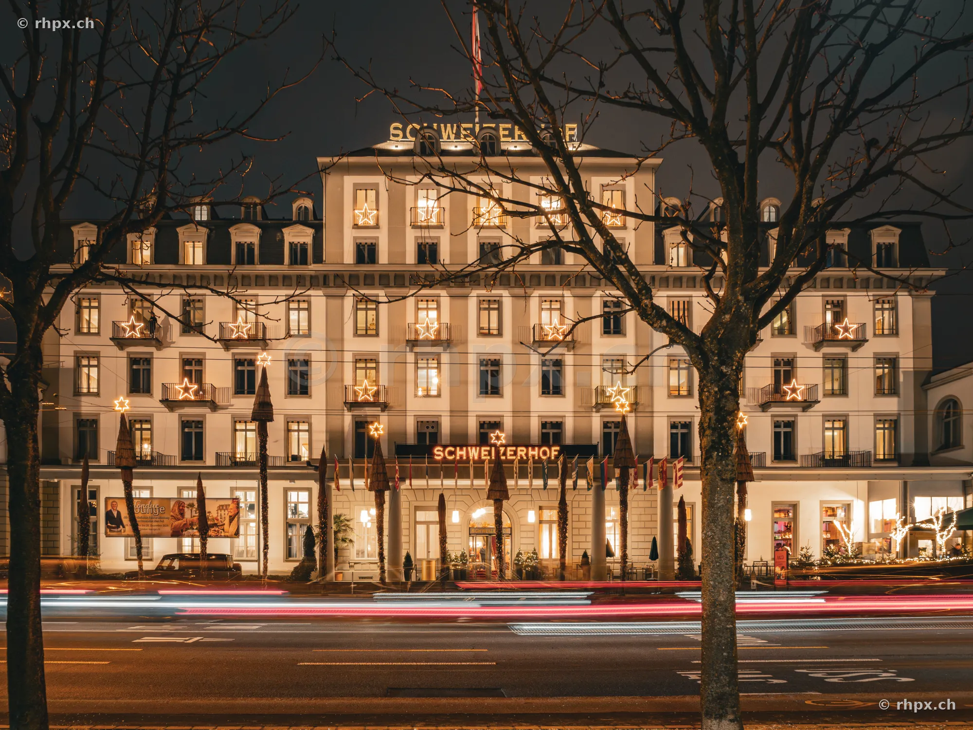 Facade of Hotel Schweizerhof Lucerne at night with Christmas star lighting on the balconies