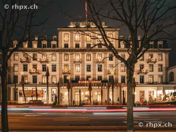 Facade of Hotel Schweizerhof Lucerne at night with Christmas star lighting on the balconies