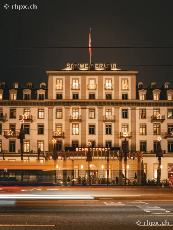 The Hotel Schweizerhof in Lucerne at night with Christmas star lighting and passing traffic
