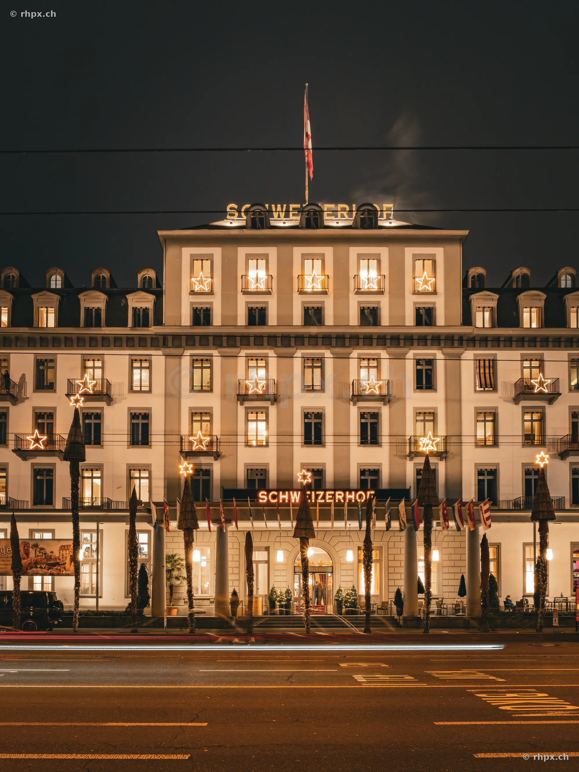 Facade of the Christmas-lit Hotel Schweizerhof on the lakeside promenade in Lucerne at night