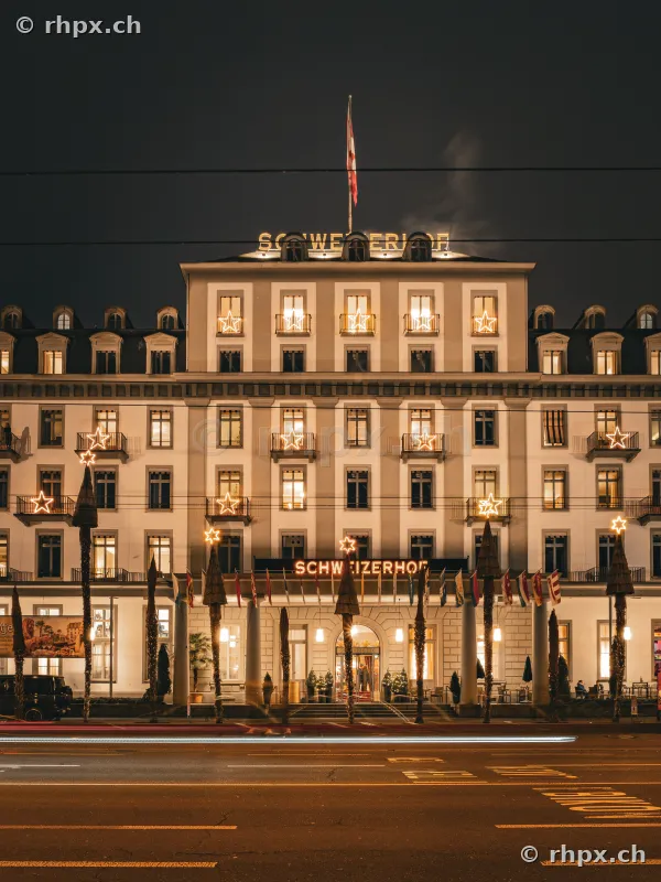 Facade of the Christmas-lit Hotel Schweizerhof on the lakeside promenade in Lucerne at night