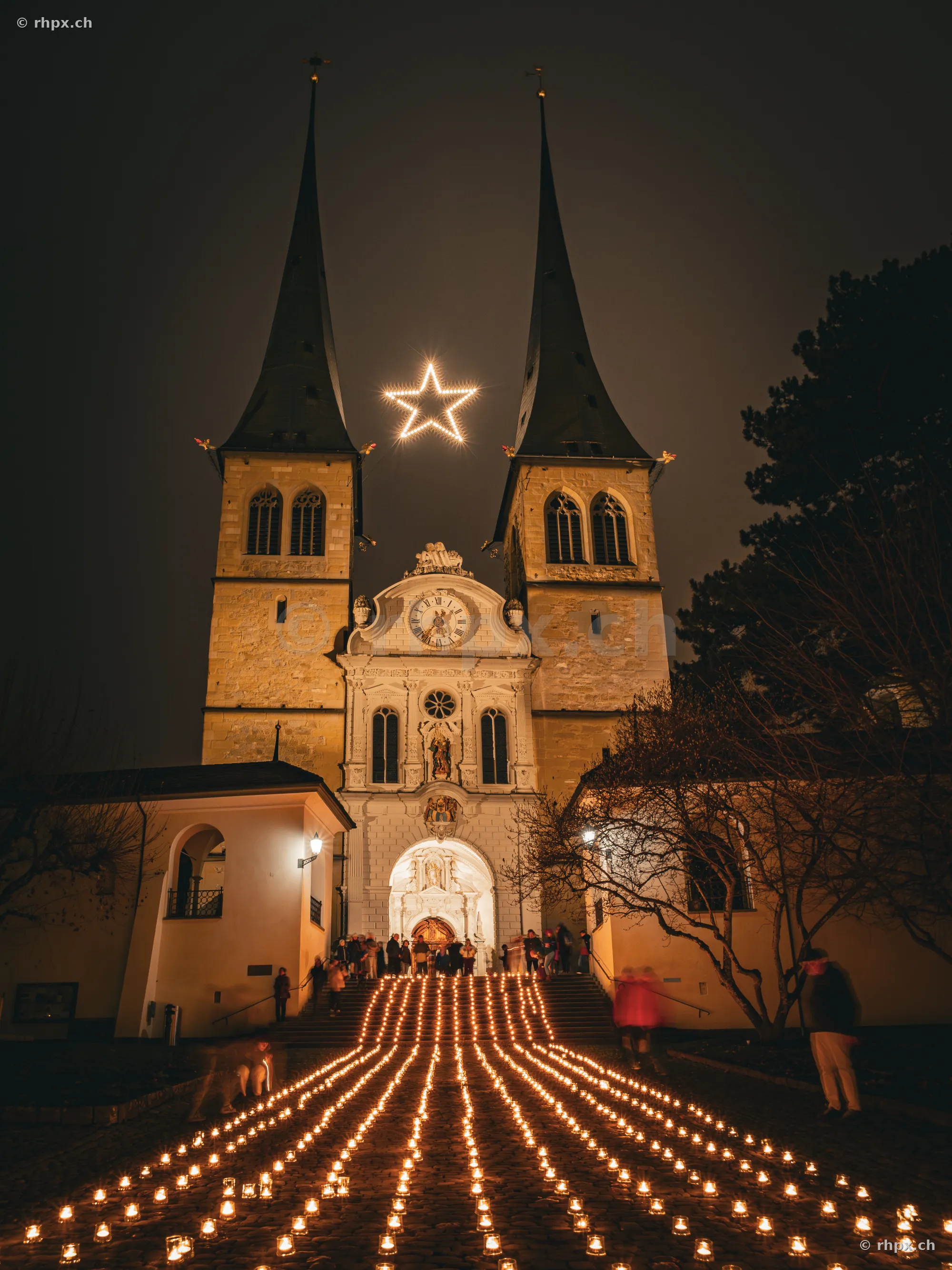 Hofkirche Lucerne at night with illuminated star and numerous candles on the steps