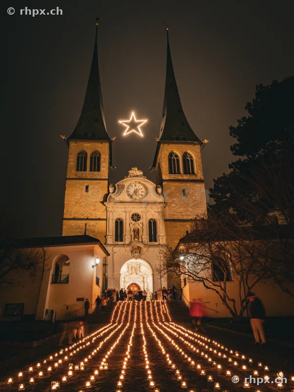 Hofkirche Lucerne at night with illuminated star and numerous candles on the steps