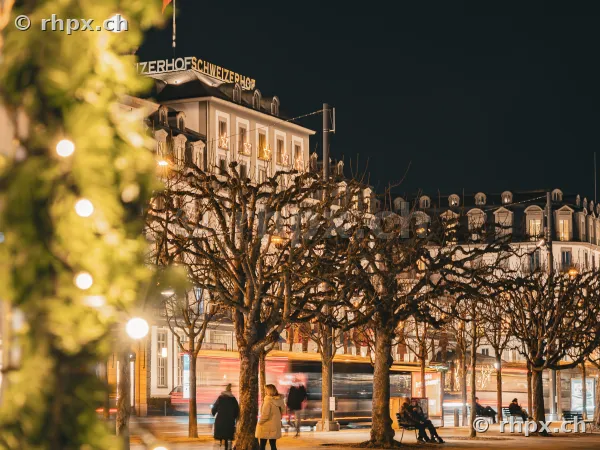 Aussenansicht des Hotel Schweizerhof in Luzern bei Nacht mit beleuchteten Bäumen im Vordergrund