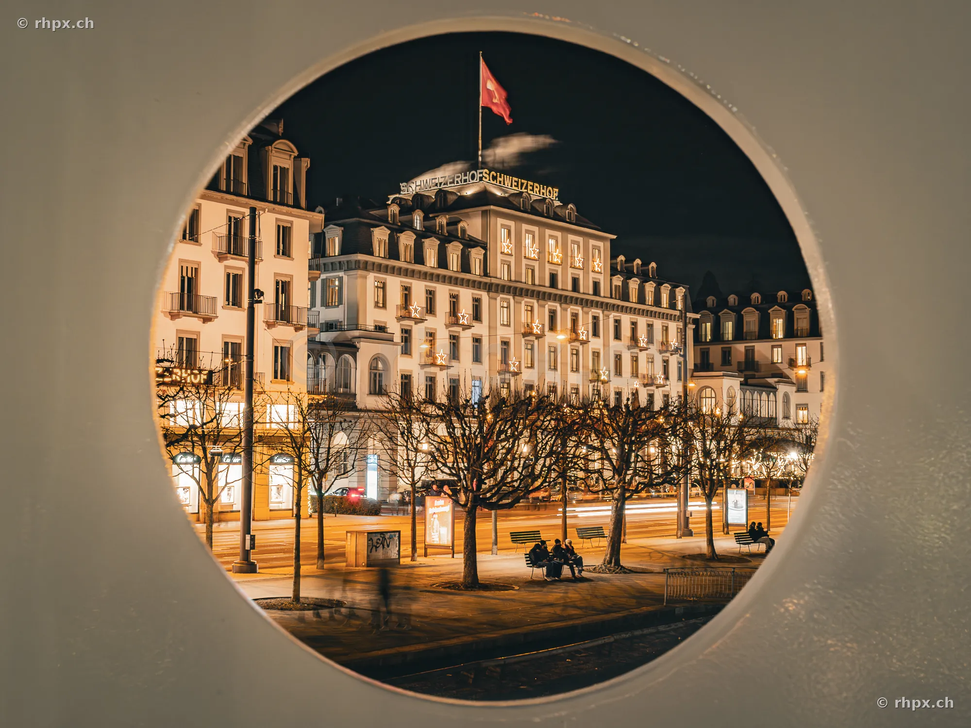Hotel Schweizerhof in Luzern nachts durch eine runde Fensteröffnung fotografiert