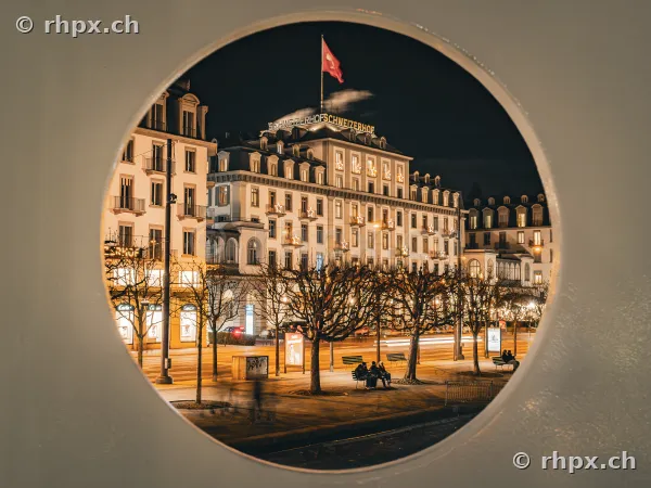 Hotel Schweizerhof in Luzern nachts durch eine runde Fensteröffnung fotografiert