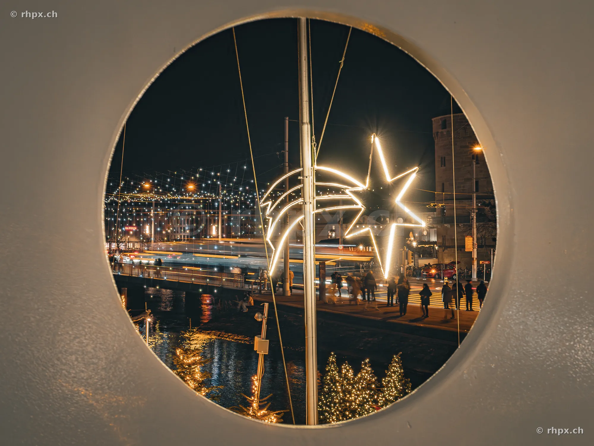 Blick durch ein rundes Fenster auf die festliche Beleuchtung in Luzern zur Weihnachtszeit