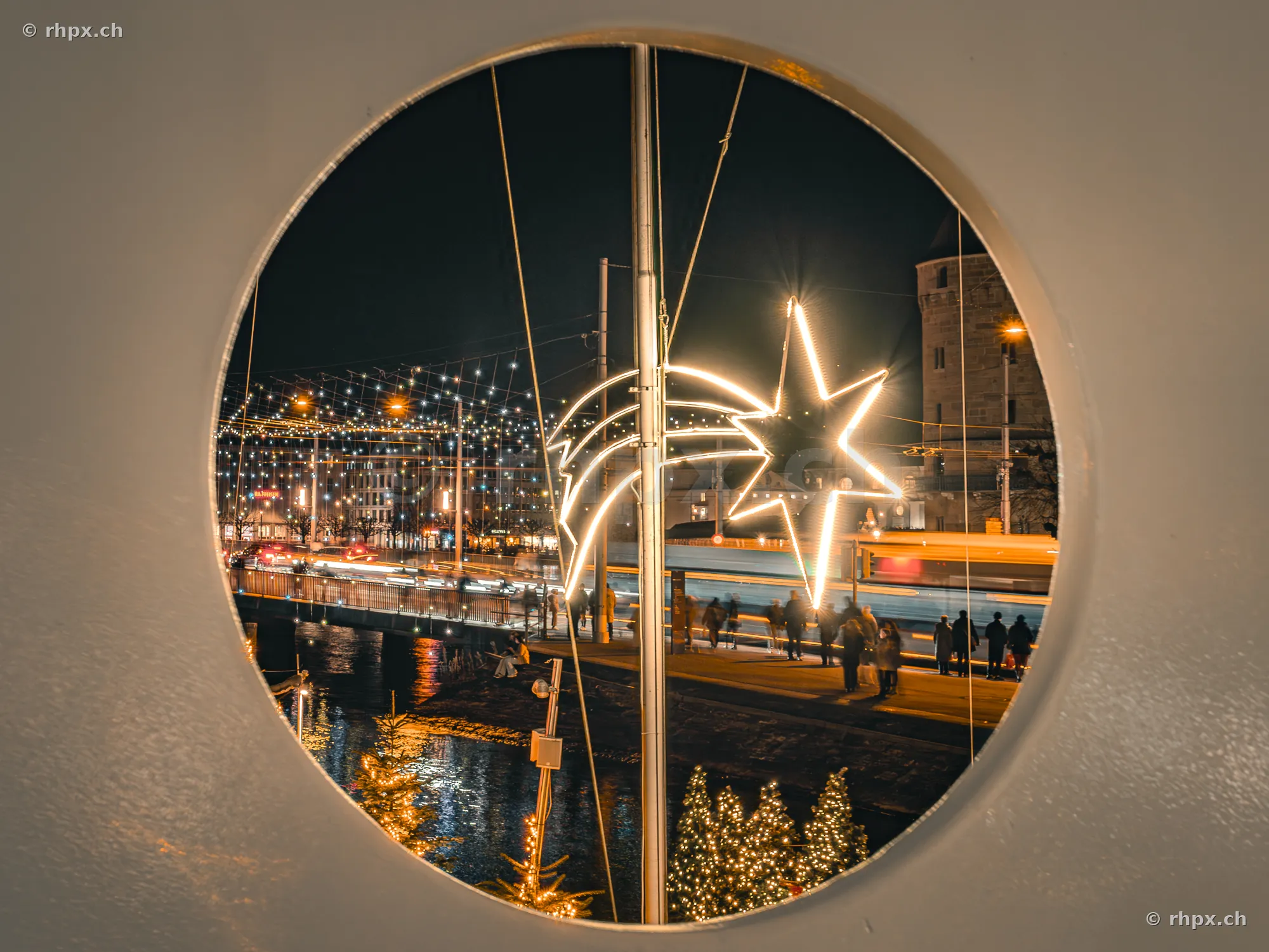 View through a circular window showing the illuminated Christmas star by the Reuss river in Lucerne.