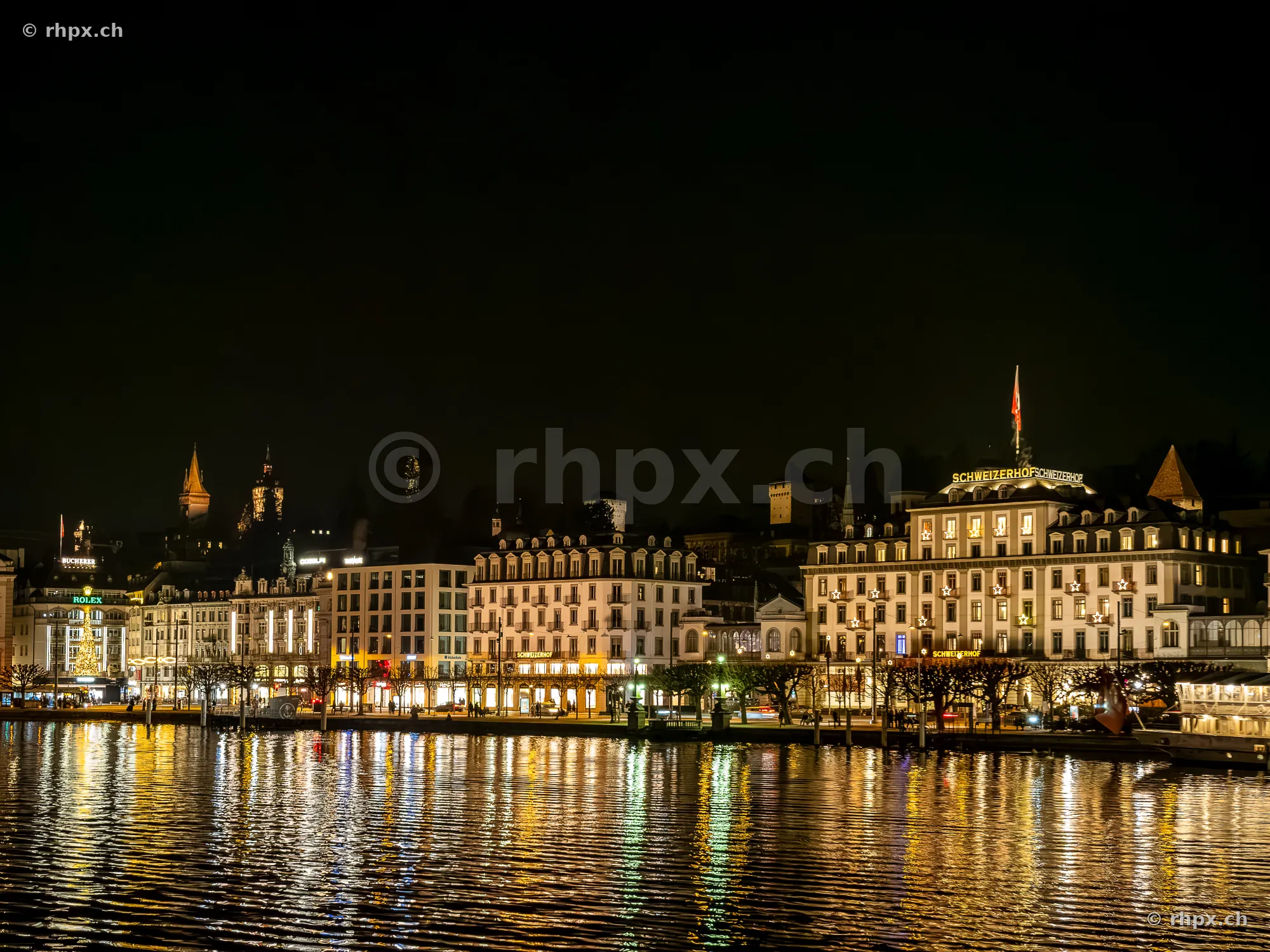 Nächtliche Ansicht des Hotels Schweizerhof und des Seeufers in Luzern bei künstlicher Beleuchtung