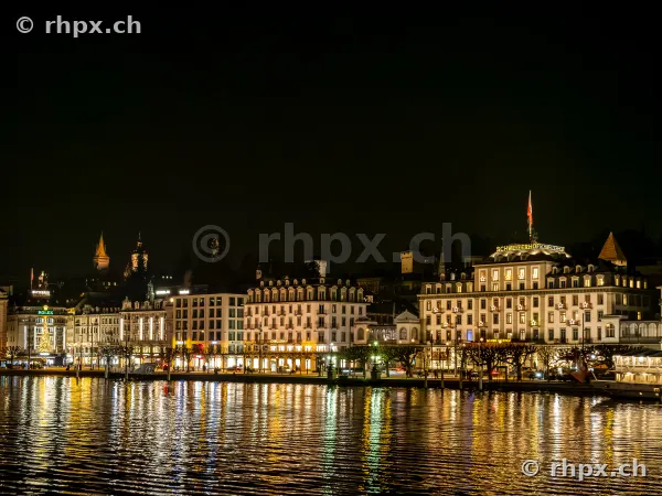 Nächtliche Ansicht des Hotels Schweizerhof und des Seeufers in Luzern bei künstlicher Beleuchtung