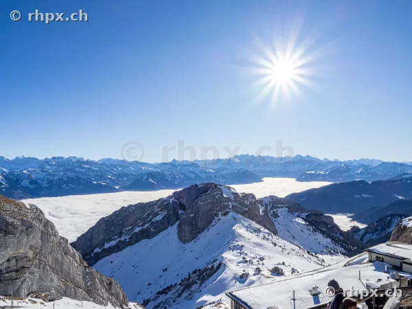 Snow-covered peak region at Mount Pilatus overlooking the sea of fog below under bright sunlight