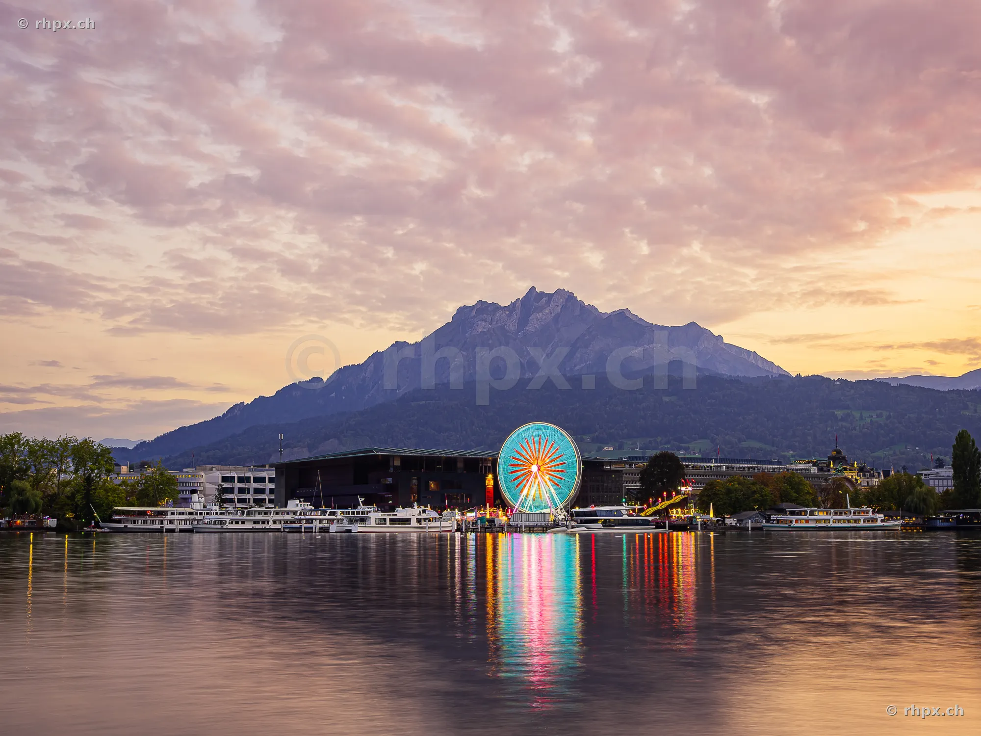 Ferris wheel at the Luzern Autumn Fair during twilight with Mount Pilatus in the background