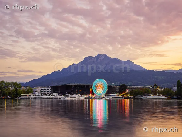 Ferris wheel at the Luzern Autumn Fair during twilight with Mount Pilatus in the background