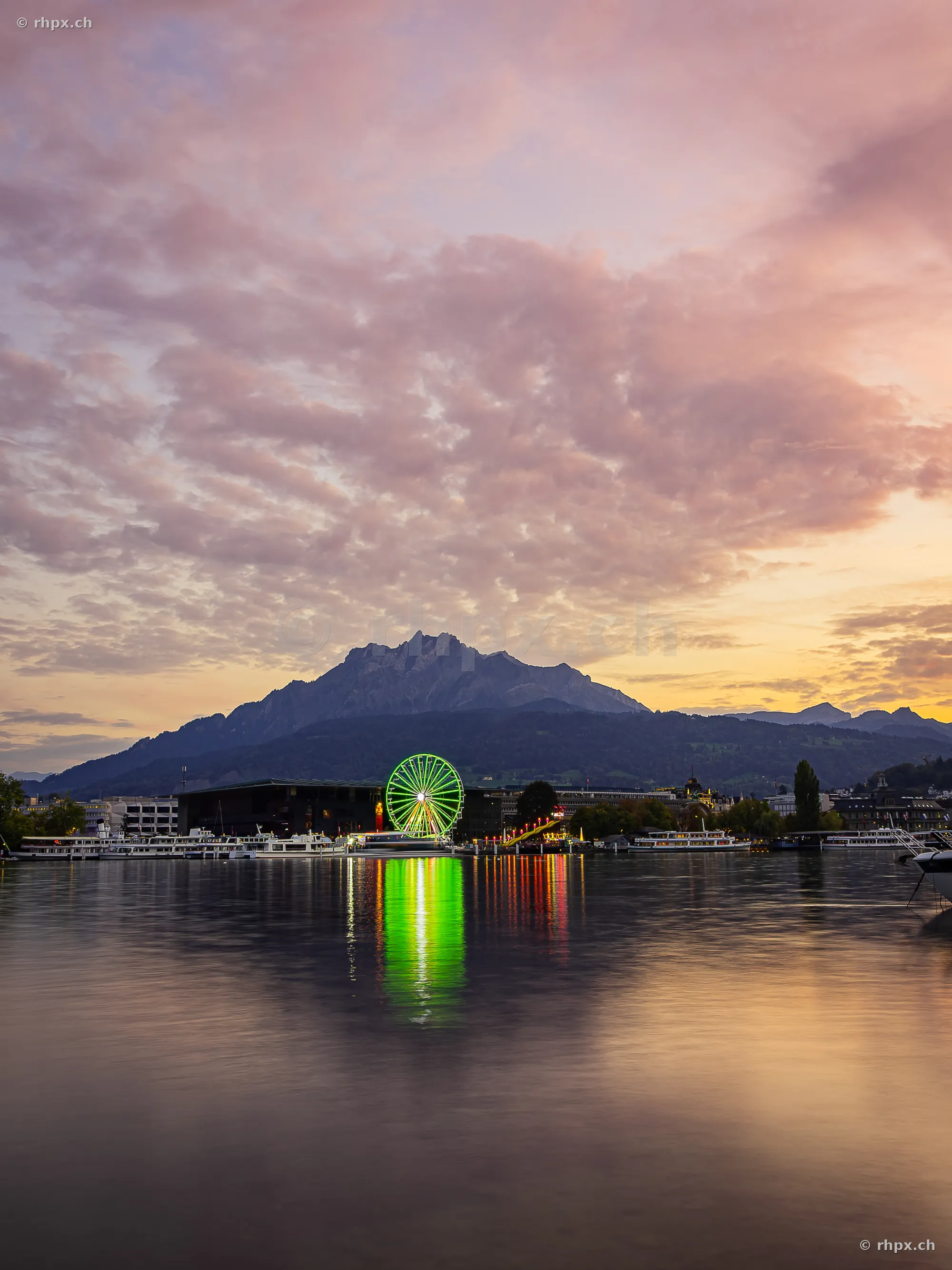 Ferris wheel of the Lucerne autumn fair at sunset in front of Mount Pilatus