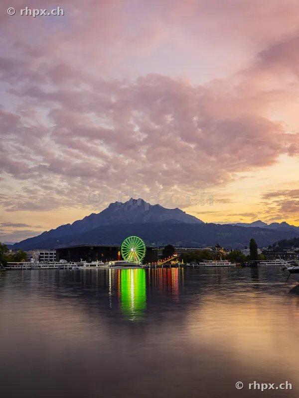 Ferris wheel of the Lucerne autumn fair at sunset in front of Mount Pilatus