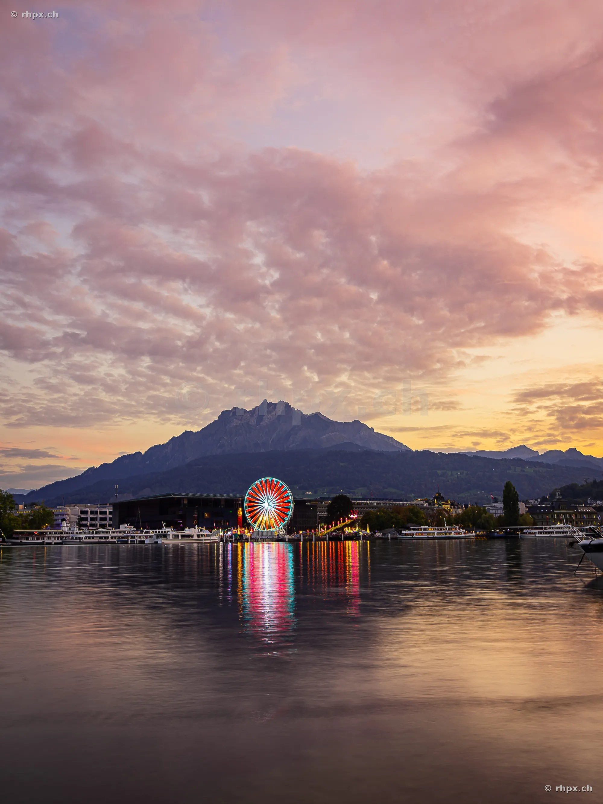Riesenrad der Lozärner Määs am Vierwaldstättersee mit dem Pilatus im Hintergrund bei Dämmerung